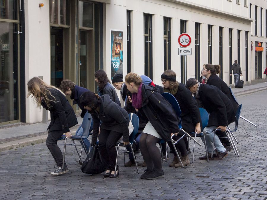zur Vergrößerungsansicht des Bildes: Studierende und Lehrende des Institus für Theaterwissenschaft bei einer Performance mit Stühlen in der Leipziger Innenstadt