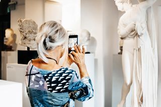 Visitor in the museum, taking a picture of a scultpture, picture: feinesbild Visitor in the museum, taking a picture of a scultpture, picture: feinesbild